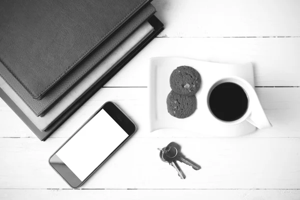 Coffee cup with cookie,phone,stack of book and key black and whi