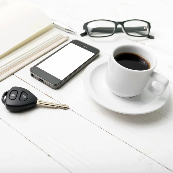 Coffee cup with phone, car key,eyeglasses and open notebook