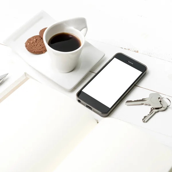 Coffee cup with cookie,phone,notebook and key