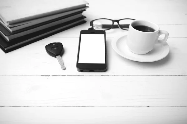 Coffee cup with phone, car key,eyeglasses and stack of book blac