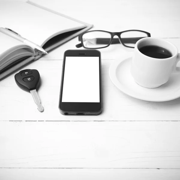 Coffee cup with phone, car key,eyeglasses and open notebook blac