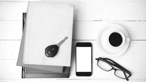 Coffee cup with phone, car key,eyeglasses and stack of book blac