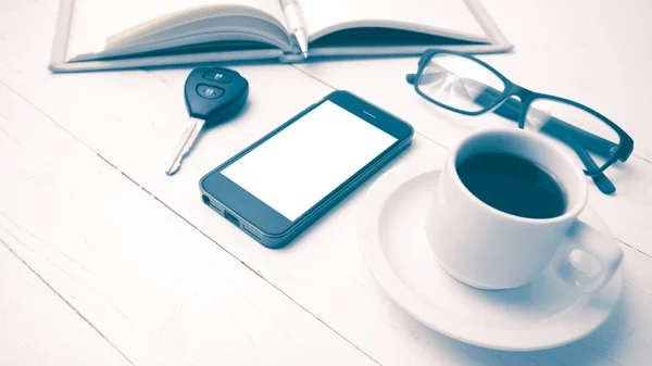 Coffee cup with phone, car key,eyeglasses and open notebook vint