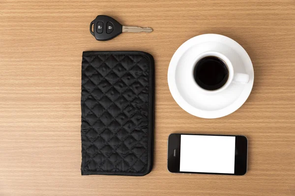 Coffee cup with phone car key and wallet