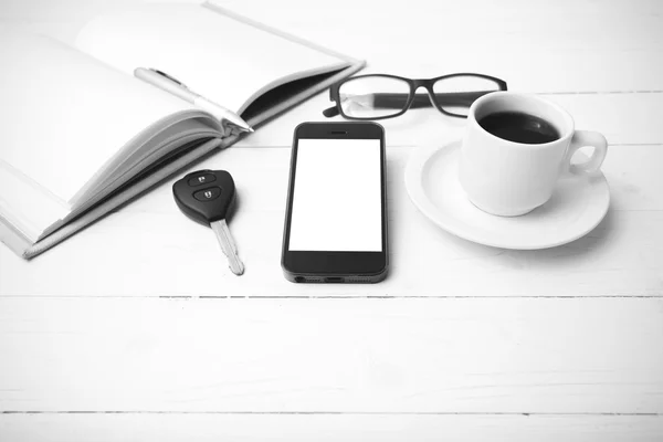Coffee cup with phone, car key,eyeglasses and open notebook blac