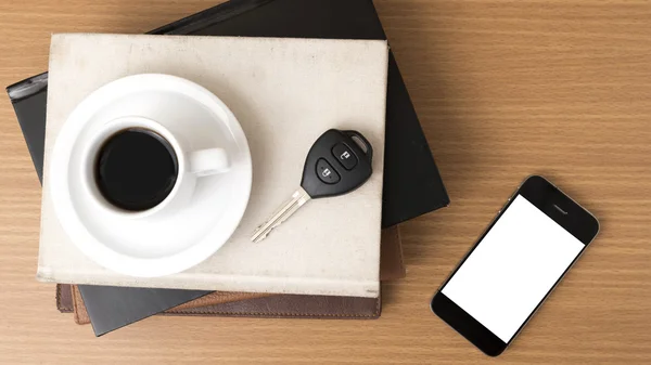 Coffee cup with phone car key and stack of book