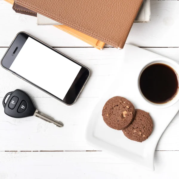 Coffe cup with cookie,phone,car key and stack of book