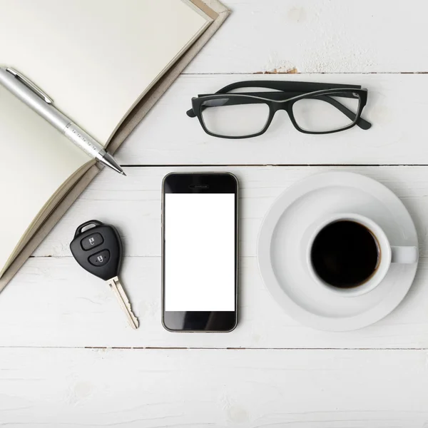 Coffee cup with phone, car key,eyeglasses and open notebook