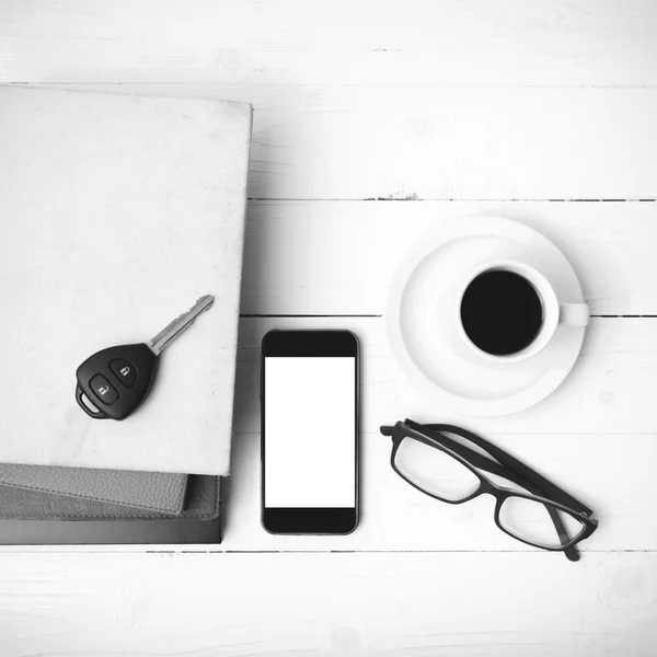 Coffee cup with phone, car key,eyeglasses and stack of book blac
