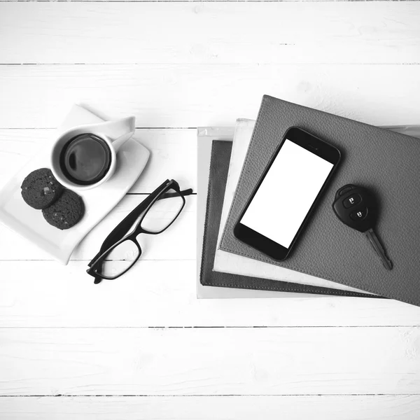 Coffe cup with cookie,phone,car key,eyeglasses and stack of book