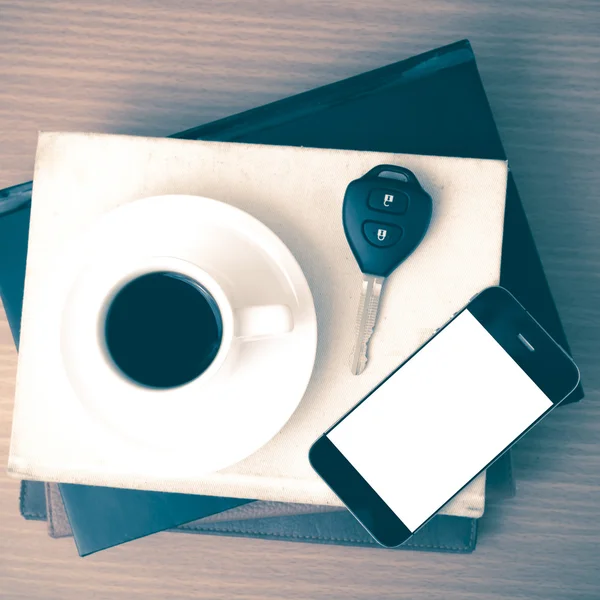 Coffee cup with phone car key and stack of book