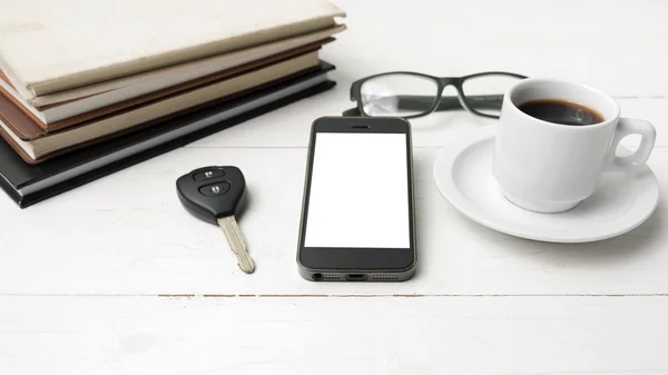 Coffee cup with phone, car key,eyeglasses and stack of book