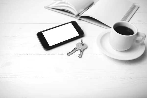 Coffee cup with phone, key and open notebook black and white col