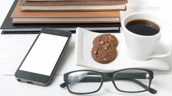 Coffee cup with cookie,phone,stack of book and eyeglasses
