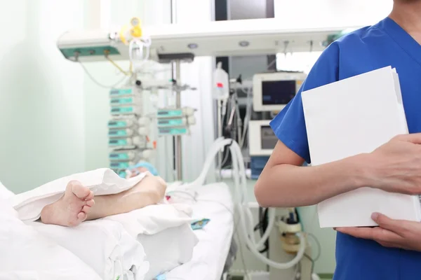 Woman doctor with a thick book in a hospital ward, near the pati