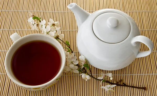 Te Tea in a cup and teapot, fresh  flowers on a background of bamboo boards .a in a cup and teapot, fresh  flowers on a background of bamboo boards .
