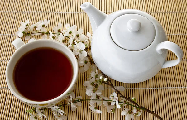 Te Tea in a cup and teapot, fresh  flowers on a background of bamboo boards .a in a cup and teapot, fresh  flowers on a background of bamboo boards .