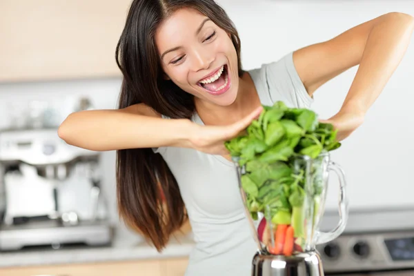 Woman making green smoothies with blender