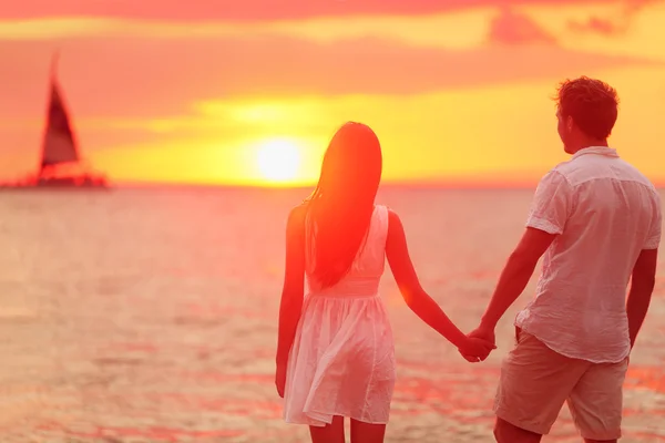 Couple holding hands at beach sunset