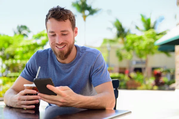 Man with smartphone drinking cold coffee