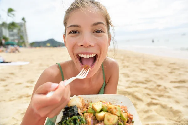 Funny woman eating salad on beach