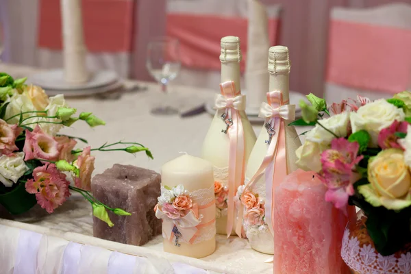 Decorated champagne bottles, candles and flowers on Wedding table with decorations in restaurant.