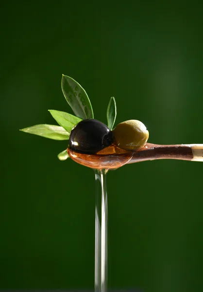 Olive oil falling on two olive with olive leaves