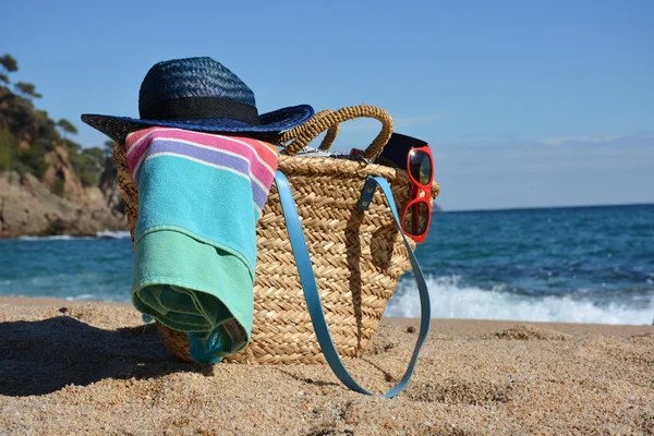 Beach bag with a book and a telephone and sunglasses