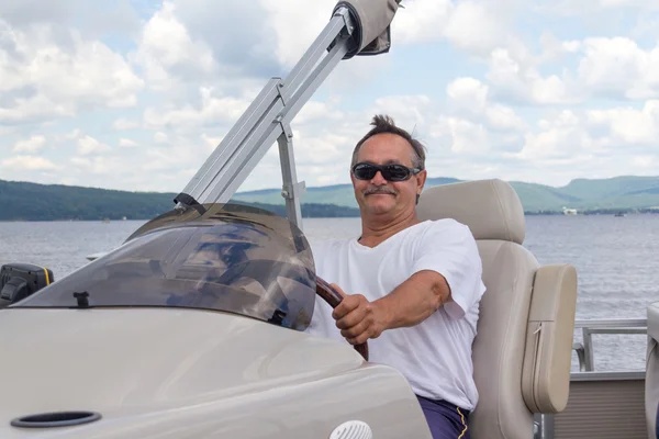 Mature men driving a pontoon boat on a lake