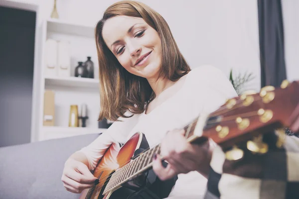 Young beautiful woman loves music and is playing guitar