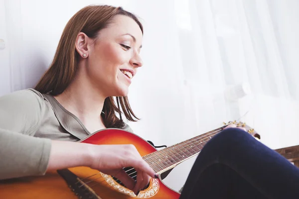 Young beautiful woman loves music and is playing guitar