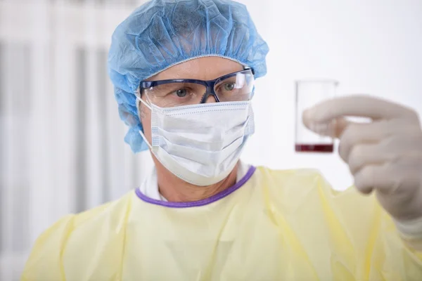 Doctor in protective gear holding blood sample