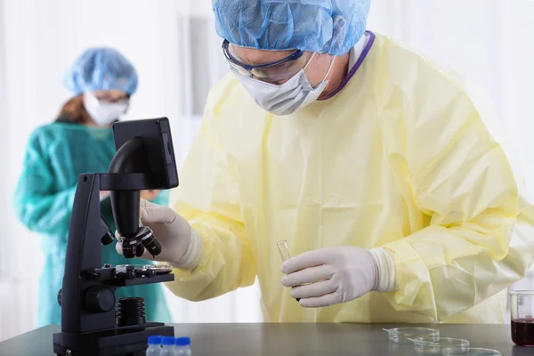 Two scientists in protective gear working in lab