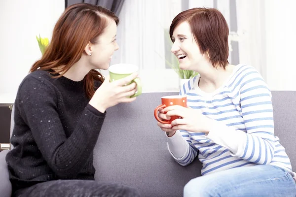 Two happy female friends with coffee cups