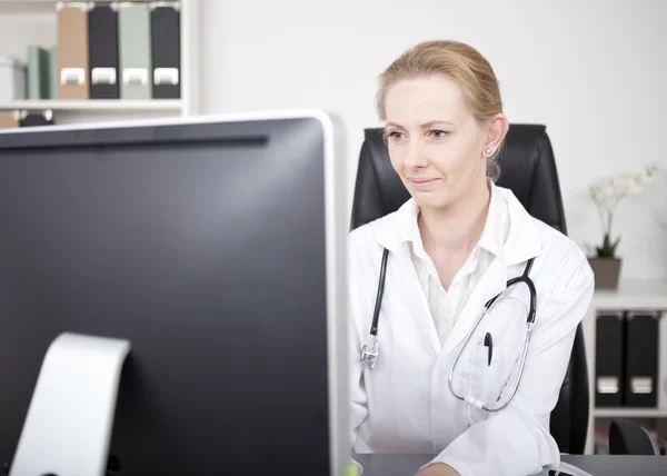 Woman Doctor Looking at Computer Monitor Seriously
