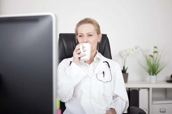 Woman Doctor Drinking Tea While Looking at Monitor