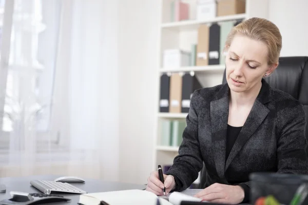 Adult Businesswoman at her Desk Writing on Paper