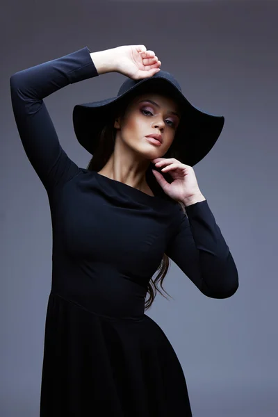 Fashion portrait of elegant woman in black hat and dress
