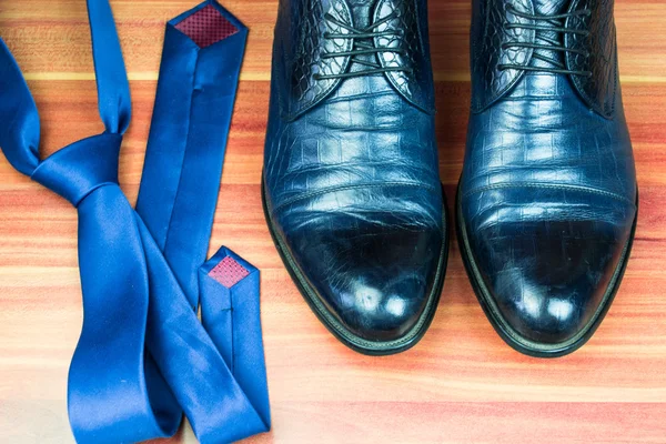 Classic men shoes and blue tie on wood background