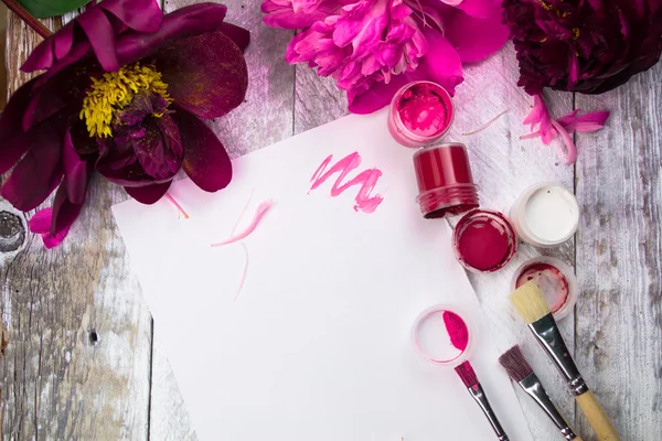 Workspace. Watercolor, paintbrush and pink peonies isolated on white background. Overhead view. Flat lay, top view