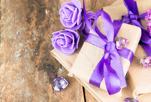 Wrapped gift boxes with presents and decorative flowers on aged wooden background. Place for text.