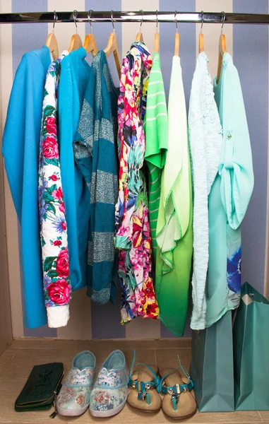 Colored female clothes on hangers in wardrobe