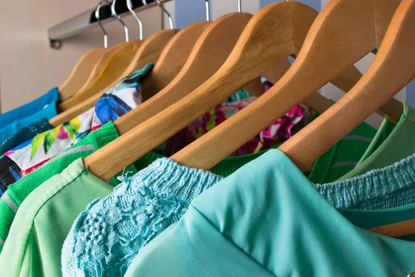 Colored female clothes on hangers in wardrobe