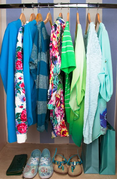 Colored female clothes on hangers in wardrobe