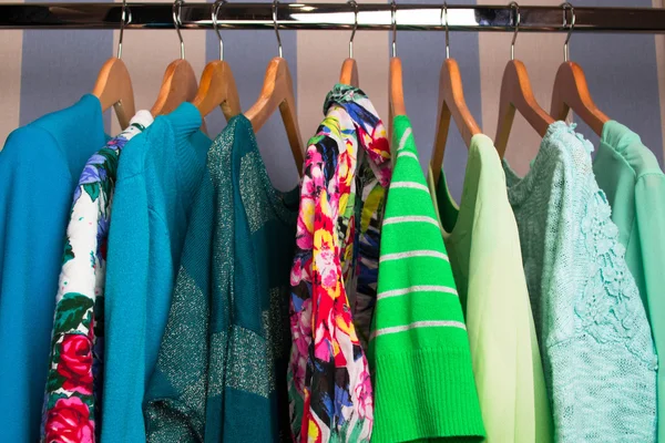 Colored female clothes on hangers in wardrobe