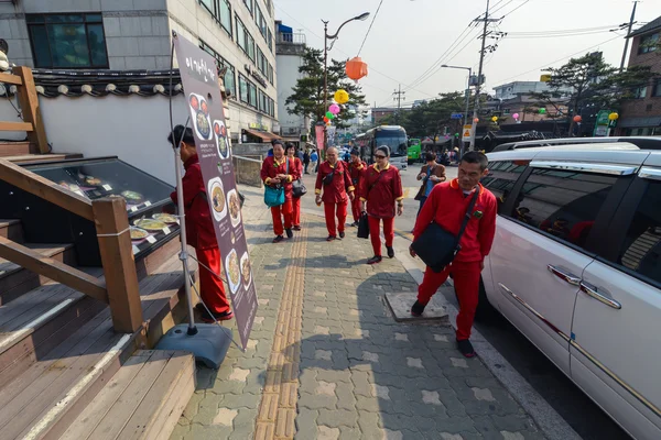 Tourist group all in red suits walking in Bukchon Hanok Village, Seoul, Korea