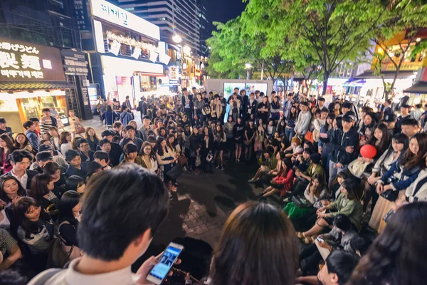Crowd of young people surrounded a street musician In Hungdae district in Seoul, Korea