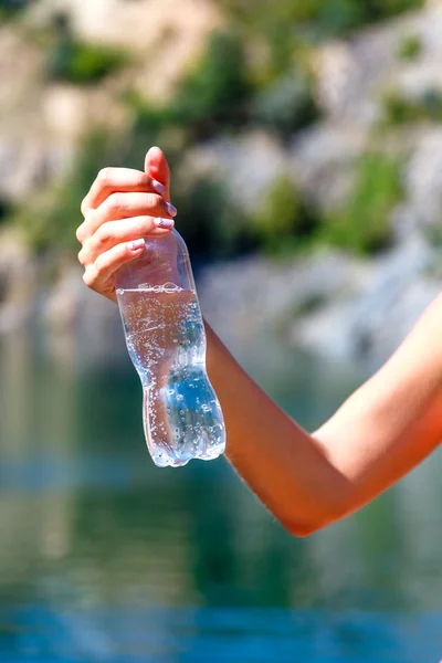 Female hand holding a bottle of mineral water outdoors