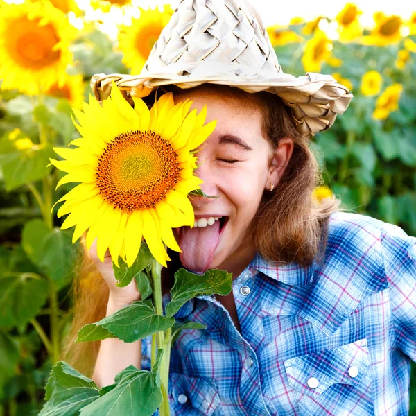 Joyful girl with sunflowers and closed eyes showing tongue