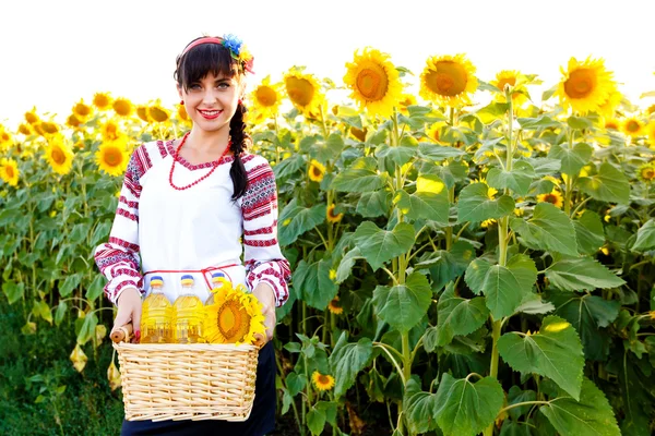 Smiling woman in embroidery holding a basket with sunflower oil